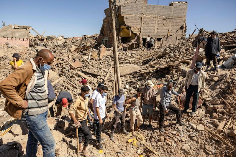 Volunteers watch as a digger moves rubble of collapsed houses in Tafeghaghte, 60 kilometres (37 miles) southwest of Marrakesh. AFP