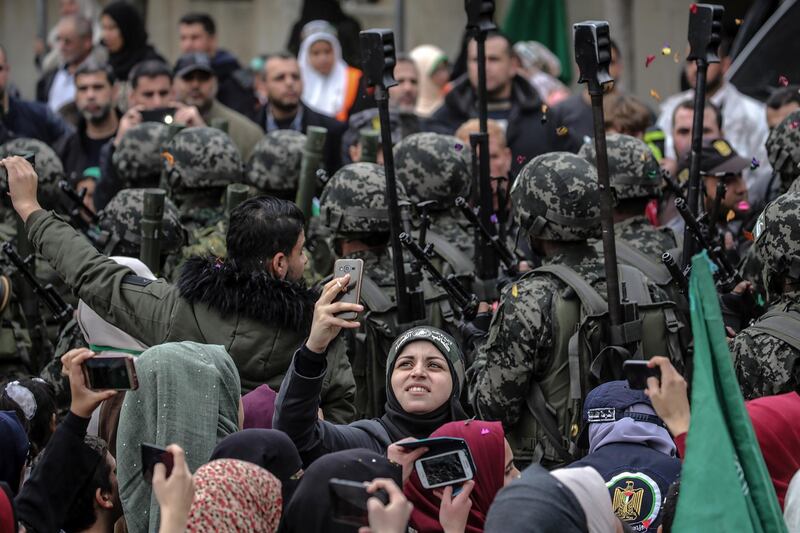 Hamas supporters take selfies with fighters of Ezz al-Din Al-Qassam Brigades, the military wing of Hamas during a rally to mark the 31st anniversary of the group, in Gaza City, Gaza Strip. EPA