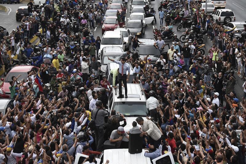 Juan Guaido, president of the National Assembly who swore himself in as the leader of Venezuela, center, stands on a vehicle during a protest against Venezuelan President Nicolas Maduro in Caracas, Venezuela, on Tuesday, March 12, 2019. Caracas began going dry Monday as the country’s power crisis put utilities out of commission, risking supplies for 5.5 million people. Photographer: Carlos Becerra/Bloomberg