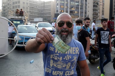 A man gestures with a currency note as Lebanese protesters block the roads with garbage bins and burning tires during protests after Lebanese Prime Minister-Designate Saad Hariri abandoned his effort to form a new government, in Beirut, Lebanon, 15 July 2021.  Hariri, who was tasked nine months ago with forming the new government, said on 15 July he is stepping down a day after he presented the cabinet proposal to President Michel Aoun who has not accepted the government.   EPA / NABIL MOUNZER