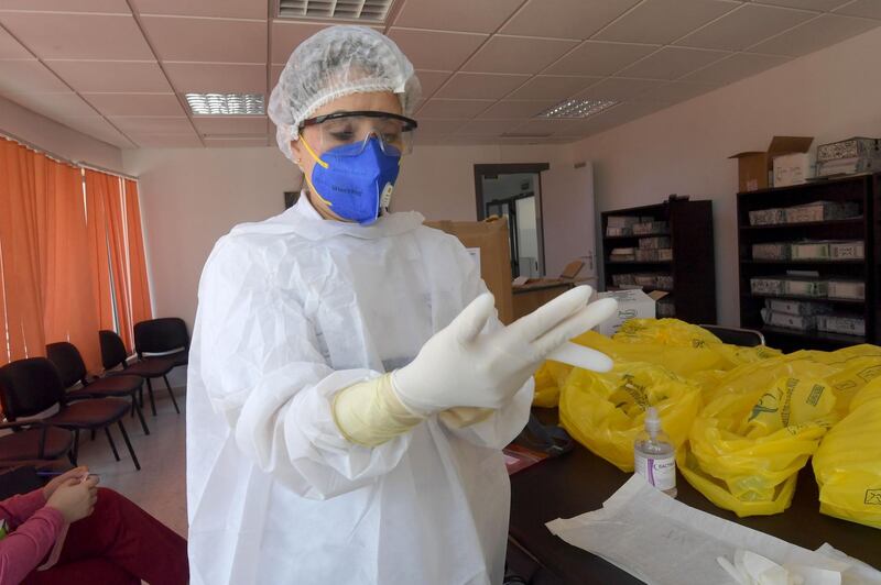 Saida Zelfani, a physician of SAMU Tunisia, dressed in personal protective equipment (PPE) puts on latex glove before attempting to get a swab sample of suspected Covid-19 patients in the capital Tunis. AFP