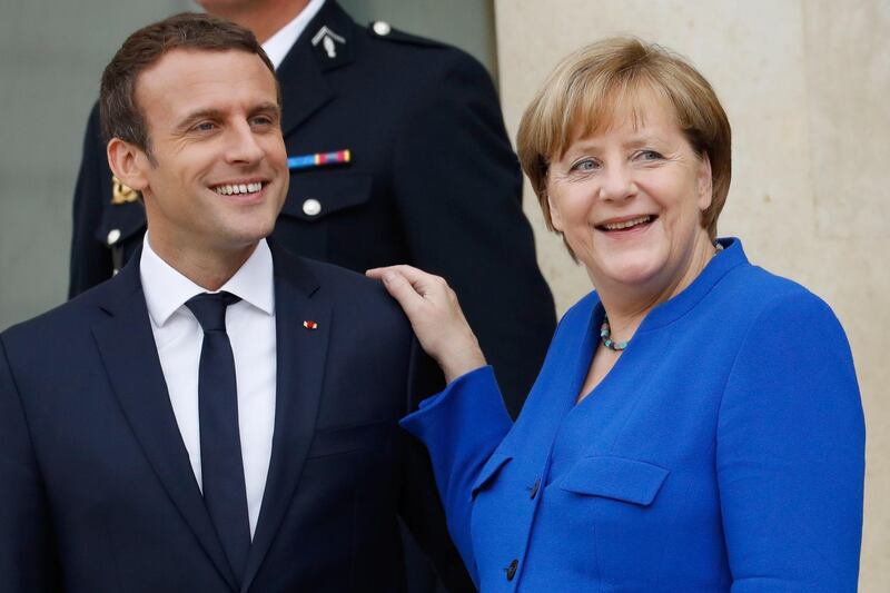 (FILES) This file photo taken on July 13, 2017 shows German Chancellor Angela Merkel (R) and French President Emmanuel Macron leaving the Elysee Palace in Paris, after an annual Franco-German Summit.  / AFP PHOTO / Patrick KOVARIK