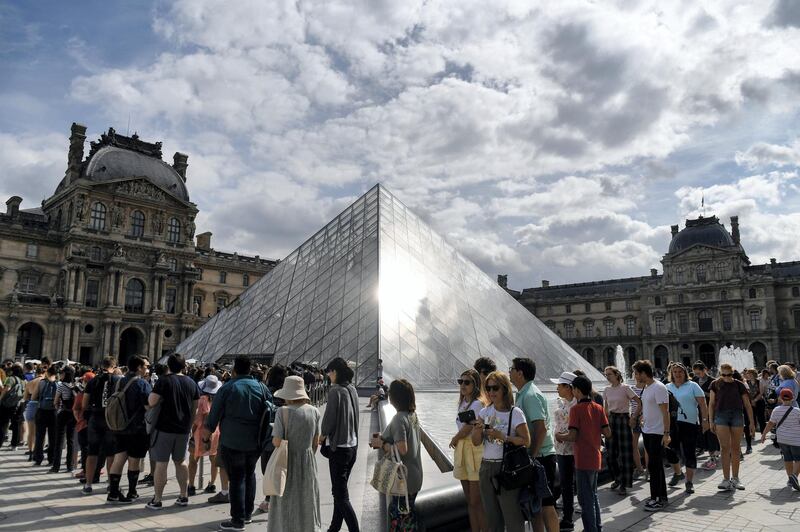 Tourists queue outside the Pyramid prior entering the Louvre museum in Paris on July 19, 2019. (Photo by ALAIN JOCARD / AFP)