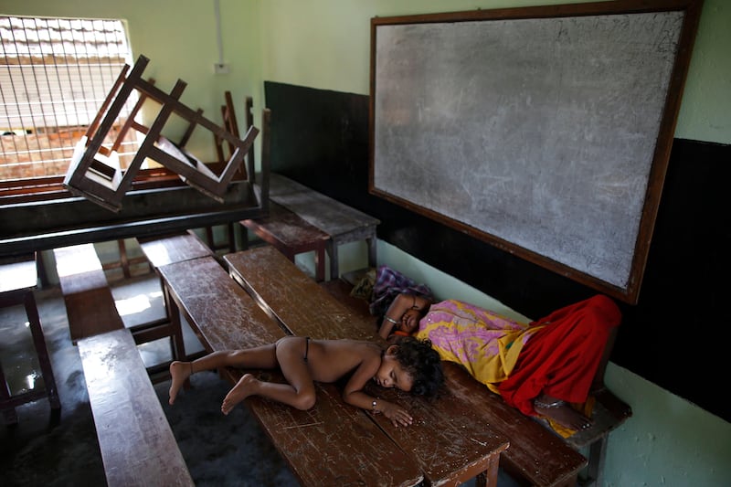 A child and a flood victim sleep in a school bench while taking a shelter in local school in Morang District, Nepal. NARENDRA SHRESTHA / EPA