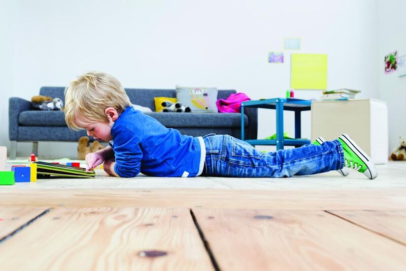 Boy playing with digital tablet on wooden floor. Getty Images