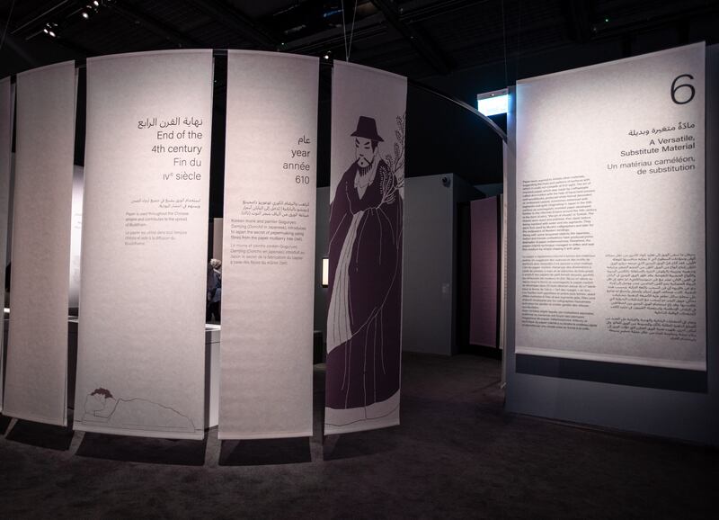 A snaking arrangement of paper banners segments the exhibition and provides historical context.
