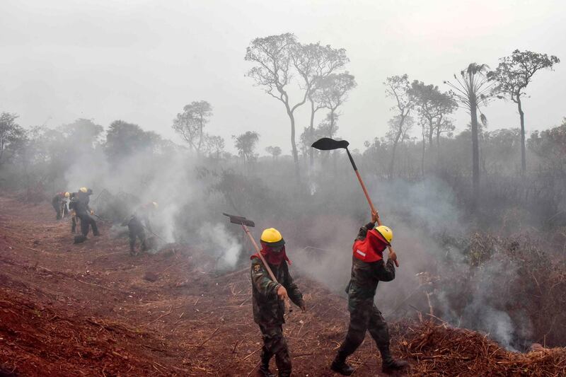 Bolivian soldiers combat forest fires in Otuquis National Park, in the Pantanal ecoregion of southeastern Bolivia, on August 26, 2019.  Like his far right rival President Jair Bolsonaro in neigboring Brazil, Bolivia's leftist leader Evo Morales is facing mounting fury from environmental groups over voracious wildfires in his own country. While the Amazon blazes have attracted worldwide attention, the blazes in Bolivia have raged largely unchecked over the past month, devastating more than 9,500 square kilometers (3,600 square miles) of forest and grassland. / AFP / Aizar RALDES
