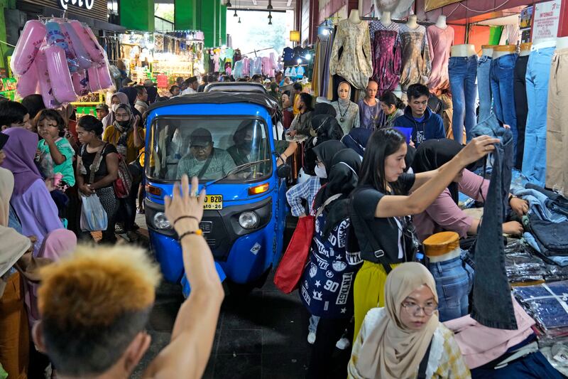 A three-wheeled taxi, known as a 'bajaj', navigates its way through Tanah Abang market in Jakarta. AP