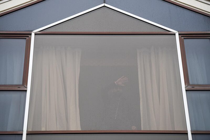 A guest gestures from a window of the Radisson Blu Edwardian hotel, a location used for travelers quarantine, at London Heathrow Airport. Bloomberg