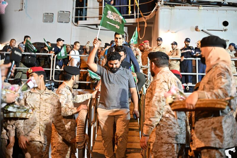 An evacuee waves a Saudi flag