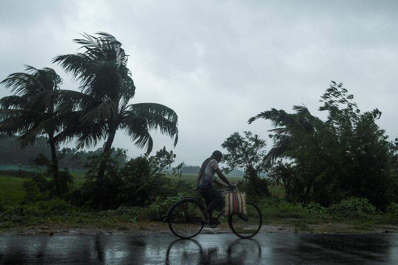 A man rides a bicycle under the rain ahead of the expected landfall of cyclone Amphan in Midnapore, West Bengal.  AFP