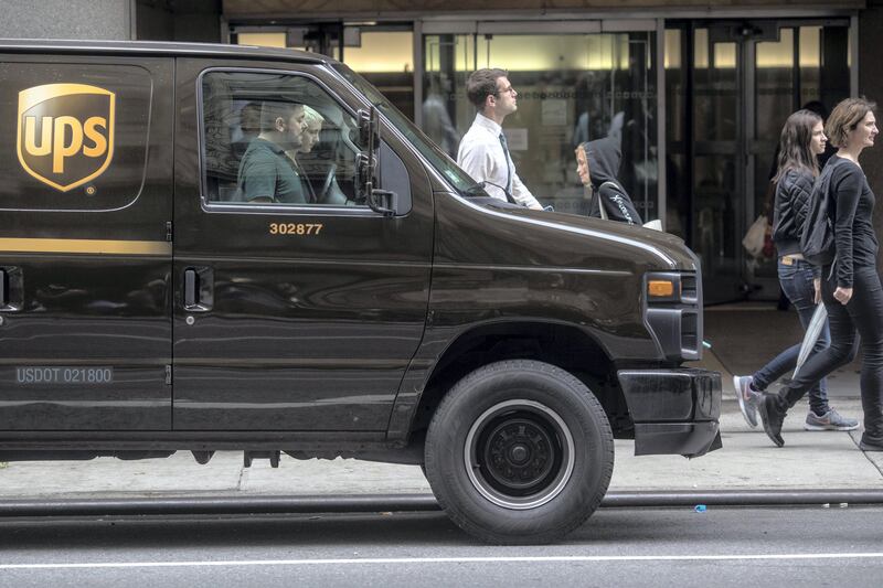 Pedestrians walk past a A United Parcel Service Inc. (UPS) delivery van on a street in New York, U.S, on Monday, July 24, 2017. United Parcel Service Inc. (UPS) is scheduled to release earnings figures on July 27. Photographer: Victor J. Blue/Bloomberg