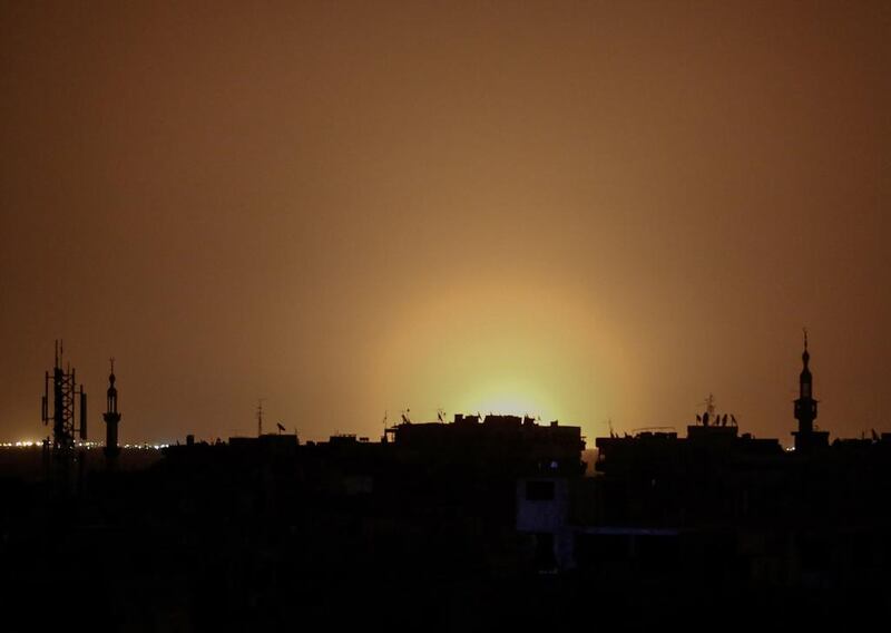 A photo taken from the rebel-held town of Douma shows flames rising in the distance which are believed to be coming from Damascus airport following an explosion early in the morning of April 27, 2017. Sameer Al Doumy / AFP Photo