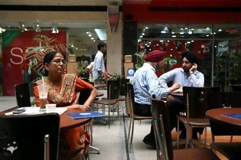 Indian people take a break with a cup of coffee at an upmarket shopping mall in the satellite town of Gurgaon. Anna Zieminski / AFP
