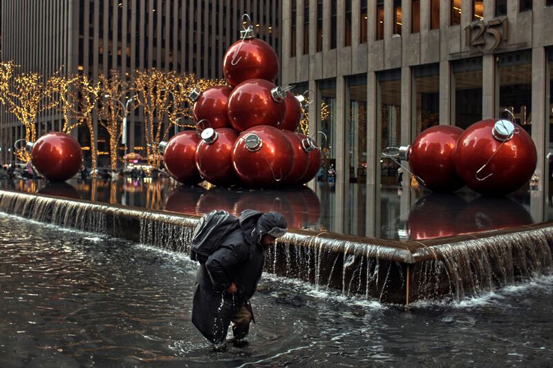 A man collects coins from a fountain on Christmas Day in New York. AP