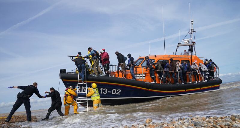 Members of the Royal National Lifeboat Institution help a group of people thought to be migrants after they were brought into Dungeness, Kent, by a lifeboat. AP