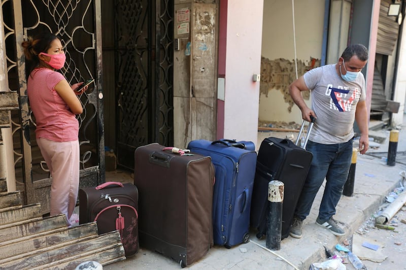 People stand with their belongings as they leave their damaged homes. Reuters