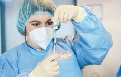 A pharmacist prepares a syringe ofAstraZeneca's  vaccine to be administered to members of the police at a COVID-19 vaccination center in Mainz, Germany, Thursday, Feb. 25, 2021. The federal state of Rhineland-Palatinate, start with the vaccination of police officers in internal police vaccination centers. (Andreas Arnold/dpa via AP)