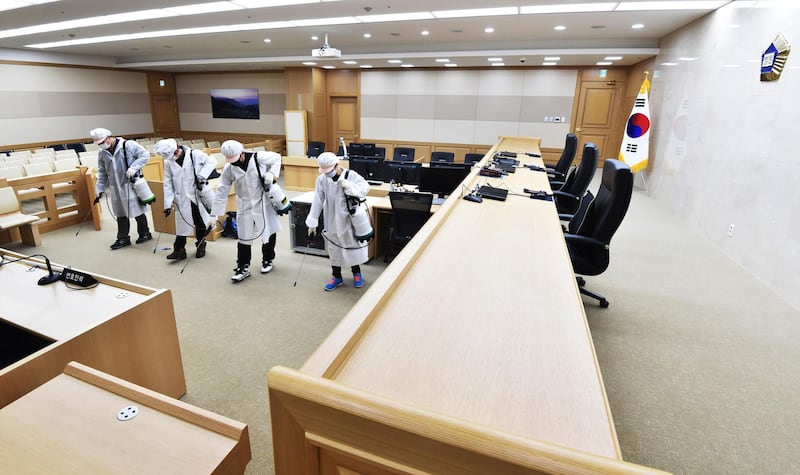 Workers wearing protective gear spray disinfectant as part of preventive measures against the spread of the COVID-19 coronavirus, in a courtroom at Suwon High Court in Suwon, South Korea.  AFP