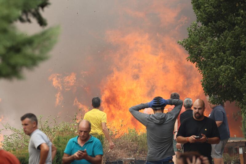 People stand near the forest fire in Anon de Moncayo, Spain. The fire has already forced the evacuation of eight villages and 1,500 people in Zaragoza province. AP