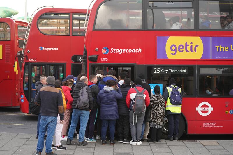 People queue to board buses outside Stratford Tube station. PA