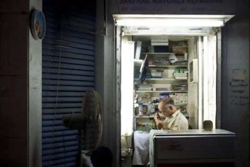 Niaz Ahmed, a watch repairman, works in his tiny store on the ground floor of an apartment tower on Hamdan Street. Ahmed arrived from Karachi, Pakistan, by ship about 40 years ago to work as a watch repairer in the old souq and is one of the few remaining vendors from the original market, which was destroyed in a fire in 2003. Antonie Robertson / The National