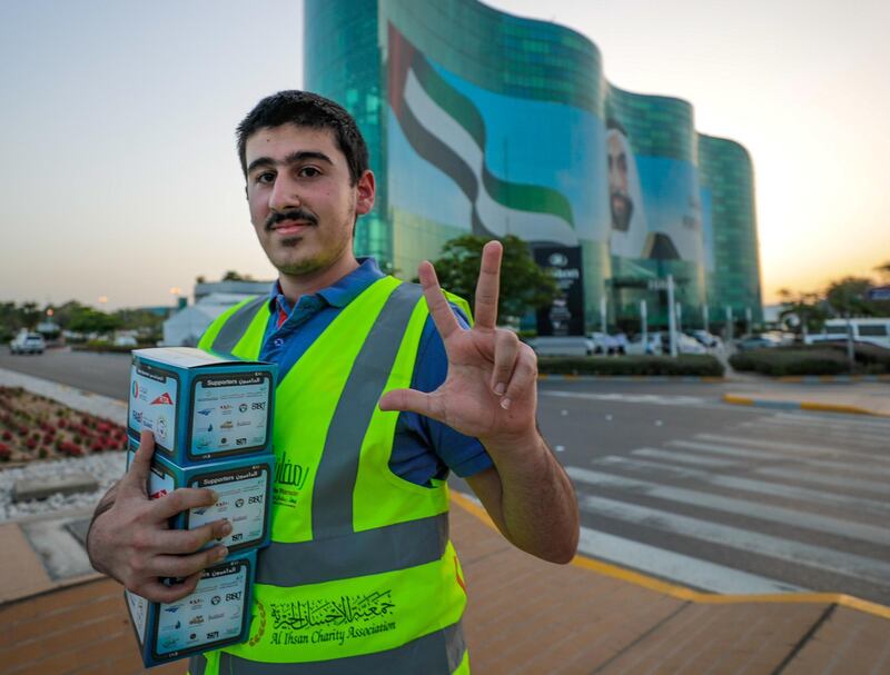 Abu Dhabi, United Arab Emirates, May 7, 2019.    Red Crescent volunteers and Abu Dhabi Police distribute food to motorists during iftar at the corner of 11th St. and 18th Sports City area. --  Mahmoud Al Hraki distibutes food at the stop light.
Victor Besa/The National
Section:  NA
Reporter:  Haneen Dajani