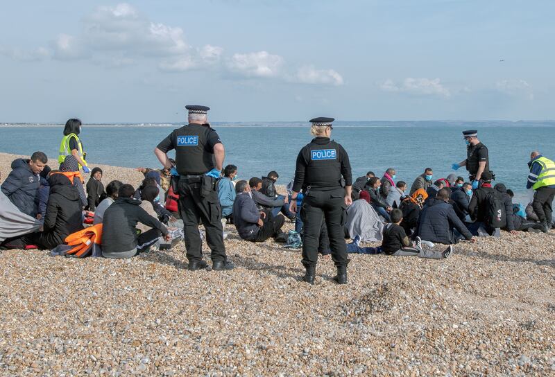 People are held on a beach after crossing the English Channel to the UK. Lord Justice Edis said there was concern with a failure of governance that allowed an unlawful policy to operate against people who made crossings to the UK for an unknown period of time. EPA