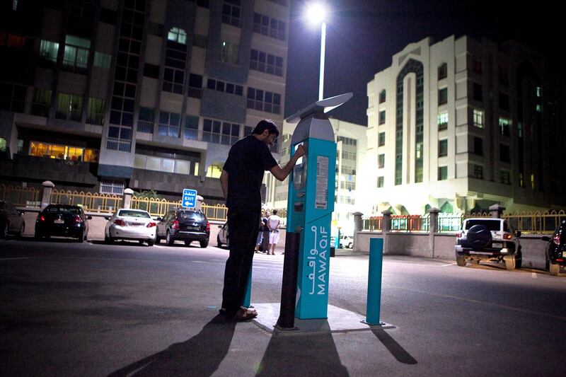 A man pays for parking in the Khalidiya neighborhood in downtown Abu Dhabi on Sunday night, Nov. 13, 2011. (Silvia Razgova/The National)

