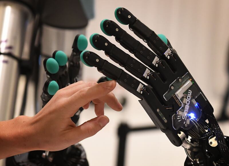 A woman touches a robotic hand produced by the Syntouch company during the Amazon Re:MARS conference on robotics and artificial intelligence at the Aria Hotel in Las Vegas, Nevada on June 5, 2019.     / AFP / Mark RALSTON

