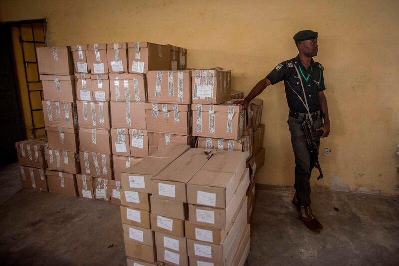 A police officer monitors boxes full of ballots for the Nigerian elections at Aba South Local Government office on February 16, 2019.  Nigerian elections have been postponed for one week, just hours before polls were due to open. Electoral material has been remove from the office and sent back to the INEC headquarter in Umuahia. Only sensitive material will stay at the Abia South Local Government until February 23, 2019.  / AFP / CRISTINA ALDEHUELA

