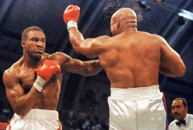 ATLANTIC CITY, NJ - APRIL 19:  Evander Holyfield (left) connects with a left hook to the chin of George Foreman as they compete for the WBC, WBA, IBF Heavyweight Titles, in a bout schedule for twelve rounds at the Trump Plaza Convention Center on April 19, 1991 in Atlantic City, New Jersey.  Holyfield defeated Foreman in a twelve round unanimous decision.  (Photo by Andrew D. Bernstein/Getty Images)