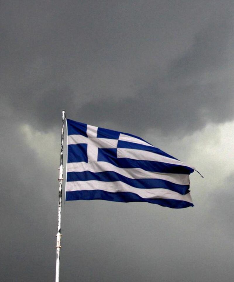 A Greek national flag flutters atop a building as dark clouds fill the sky in Athens. Alkis Konstantinidis / Reuters