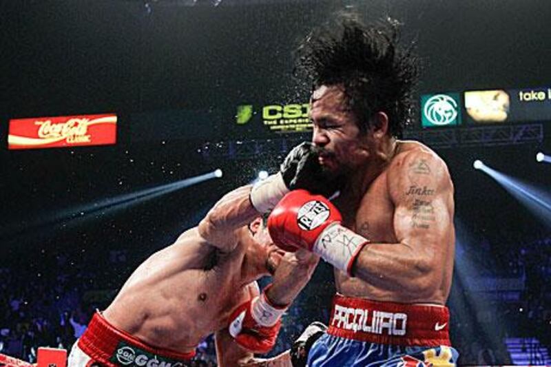 Juan Manuel Marquez, left, breaches Manny Pacquiao's defences during their WBO welterweight bout in Las Vegas. Pacquiao's trainer, Freddie Roach, said that the Mexican deserves another match before Pacquiao's team turn their focus to Floyd Mayweather Jr.