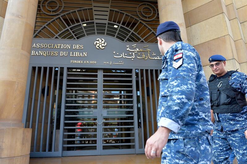 Lebanese policemen walk in front of the building of the Lebanese Association of Banks after anti-government protesters locked the main entrance by a chain and lock during ongoing protests against the banks' policies and the government in downtown Beirut, Lebanon.  EPA