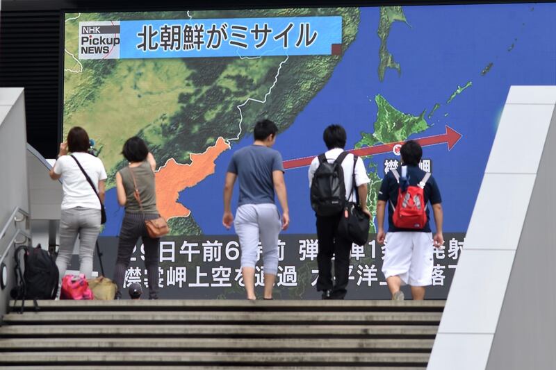 Journalists film as pedestrians walk in front of a huge screen displaying a map of Japan (R) and the Korean Peninsula, in Tokyo on August 29, 2017, following a North Korean missile test that passed over Japan.
Japanese Prime Minister Shinzo Abe said on August 29 that he and US President Donald Trump agreed to hike pressure on North Korea after it launched a ballistic missile over Japan, in Pyongyang's most serious provocation in years. / AFP PHOTO / Toshifumi KITAMURA