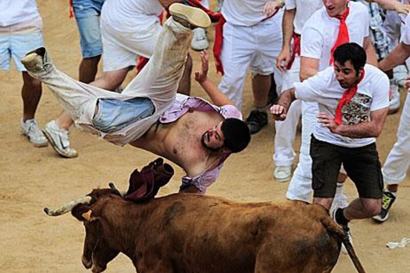 A reveller is tossed by a bull in the bullring, at the end of third running of the bulls at the San Fermin festival.