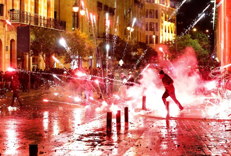 Anti-government protesters throw firecrackers at riot police during a demonstration against the new government, near Parliament Square, in Beirut, Lebanon. AP Photo