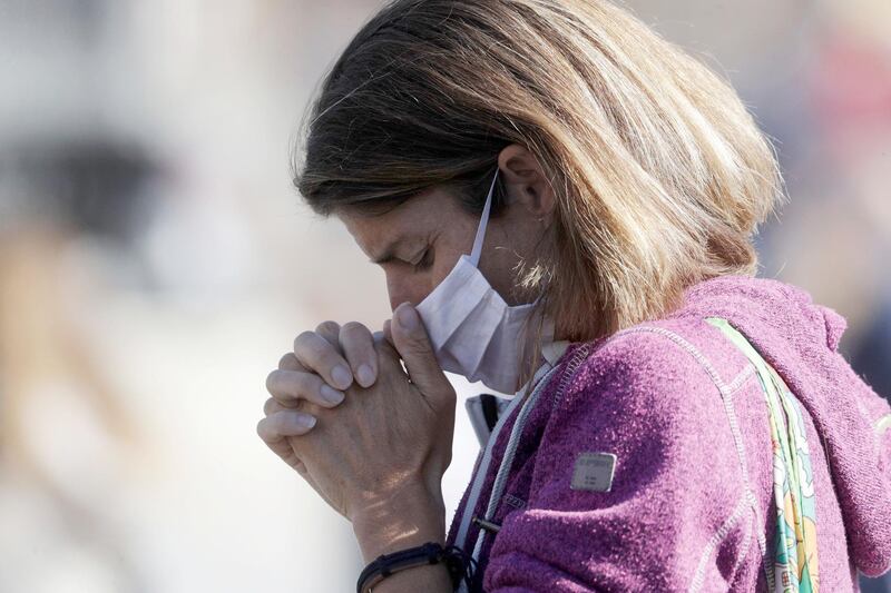 A woman wearing a face mask to curb the spread of Covid-19 holds her hands as she prays during Pope Francis' Angelus noon prayer in St Peter's Square at the Vatican. AP Photo