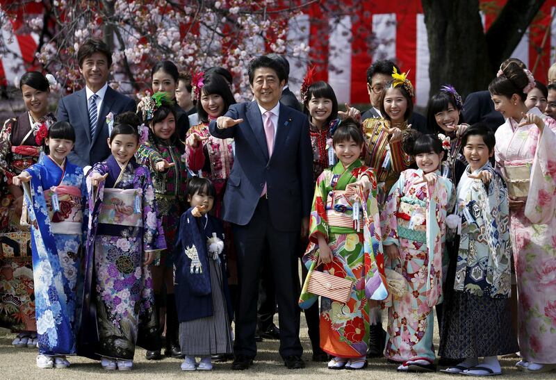 Japan's Prime Minister Shinzo Abe poses with child actors, members of Japanese idol group Momoiro Clover Z at a cherry blossom viewing party at Shinjuku Gyoen park in Tokyo, Japan. REUTERS