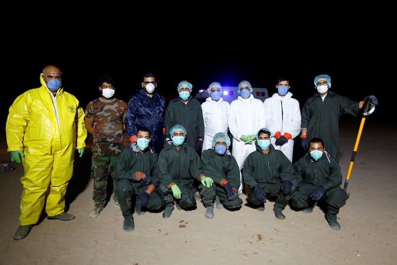 Members of the Popular Mobilization Forces, and Shiite students of Al Hawza Al Ilmiyya, who volunteered to work at the cemetery, wear protective suits as they pose for a group photo at the new Wadi Al Salam cemetery dedicated to those who died of coronavirus disease, on the outskirts of the holy city of Najaf. REUTERS