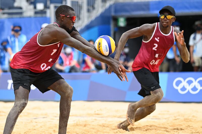 Qatar's Ahmed Tijan (R) watches as partner Cherif Younousse digs the ball on their way to winning the men's beach volleyball bronze medal match against Latvia at Shiokaze Park in Tokyo.