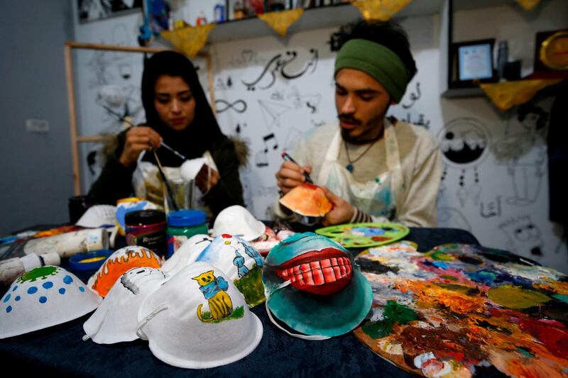 Palestinian artists Samah Said (L) and Dorgham Krakeh (R) paint masks for a project raising awareness about the COVID-19 coronavirus pandemic, in Gaza City.   AFP