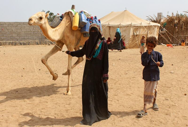 A displaced woman and child who fled from the western coastal city of Hodeidah due to the ongoing civil war between the Saudi-backed government and Huthi rebels, walk leading a camel at a make-shift camp following their arrival in Aden on January 1, 2017.  / AFP PHOTO / SALEH AL-OBEIDI