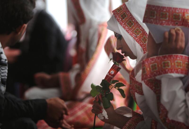 A Palestinian bride smells a rose during the mass wedding ceremony in Gaza City on April 11. Mahmud Hams / AFP