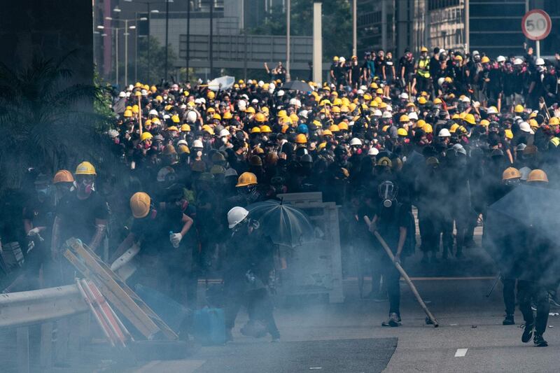 Protesters react after police fired tear gas at Kowloon Bay in Hong Kong's Kwun Tong district on Saturday. AFP