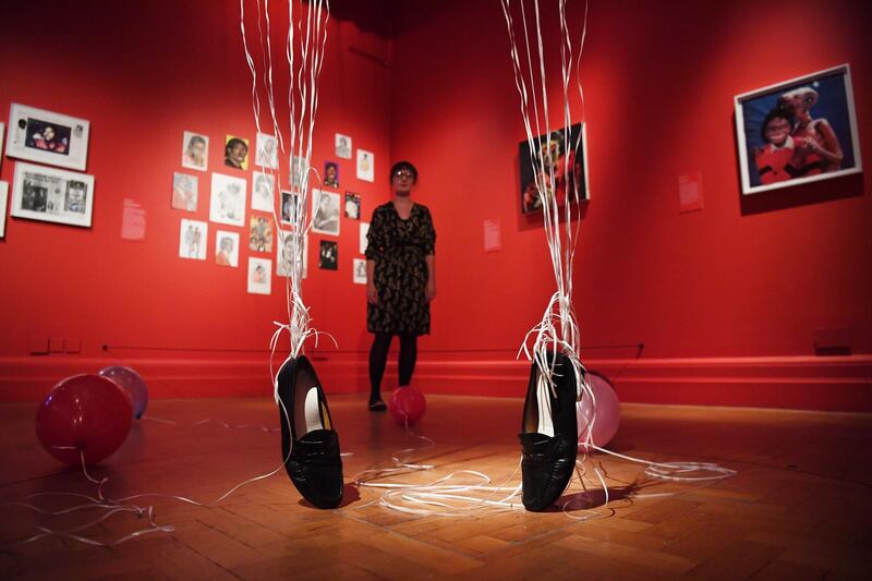 A woman poses amongst shoes suspended by balloons during a press preview of the exhibition "Michael Jackson: On the Wall" at the National Portrait Gallery in London, Britain, on June 27, 2018. Neil Hall / EPA