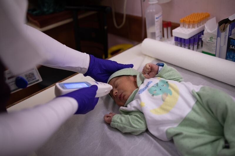 A nurse checks the temperature of a newborn baby.

