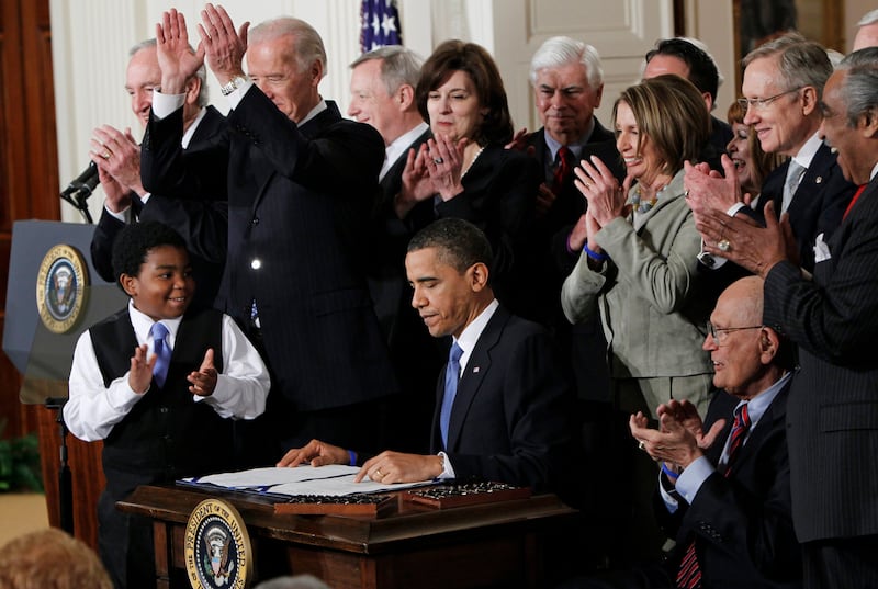 Then-president Barack Obama is applauded after signing the Affordable Care Act into law in the East Room of the White House in Washington with Joe Biden. AP
