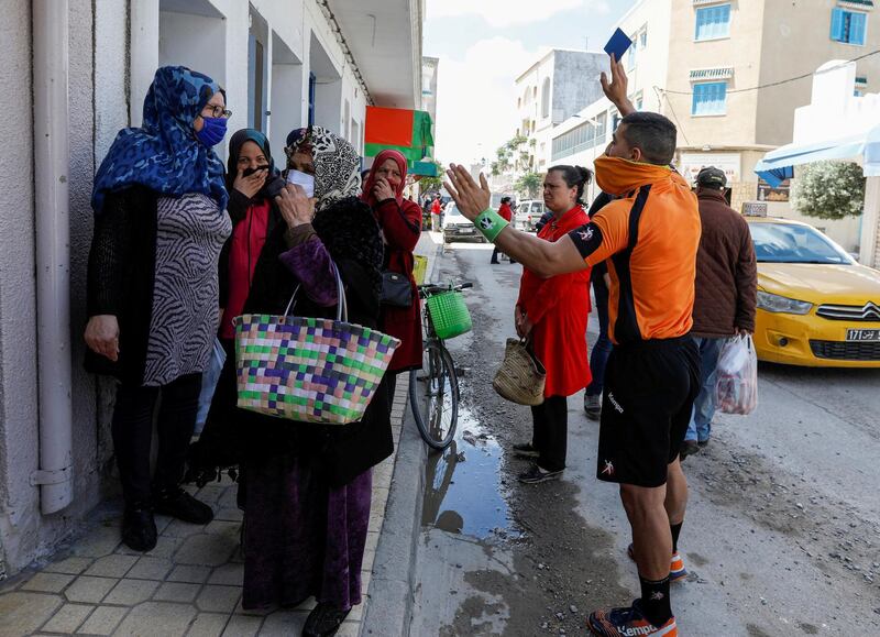 Abdelhak Etlili, a 19-year-old handball referee, issues a blue card for women gathered outside a shop and violating social distancing rules at the coastal town of Nabeul, Tunisia. Reuters